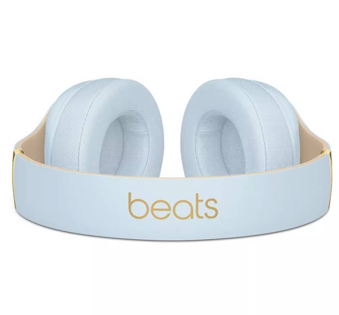 A light blue and gold pair of over-ear headphones with the word &quot;beats&quot; on the headband