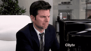 Ben from Parks and Recreation looks disgusted as he moves away from his computer screen