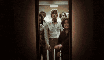 Zombies from Dawn of the Dead charge into an elevator towards the camera while the doors slowly open