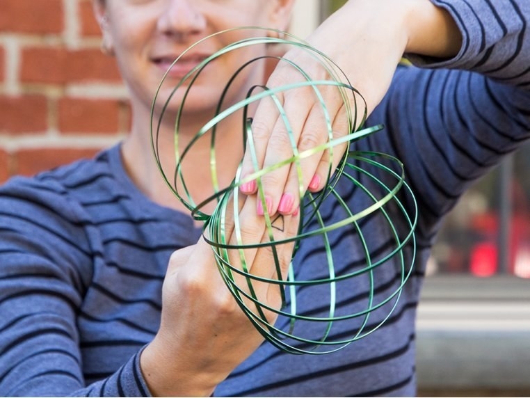 Model playing with the spherical-shaped spiral toy between their hands