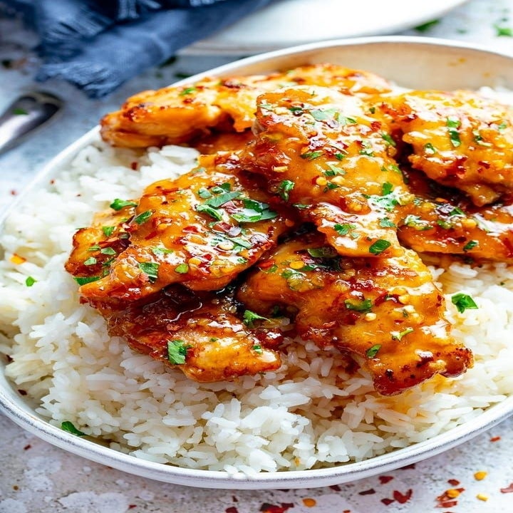 A bowl of rice topped with crispy honey garlic chicken.