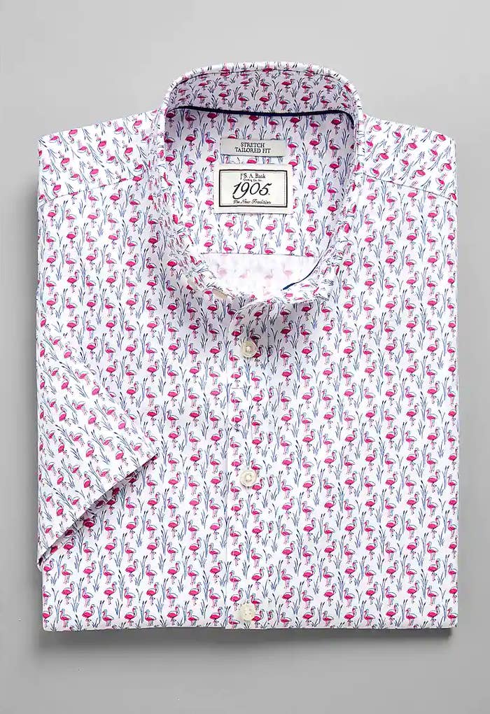 A folded white collared short-sleeve shirt with a bright pink flamingo pattern