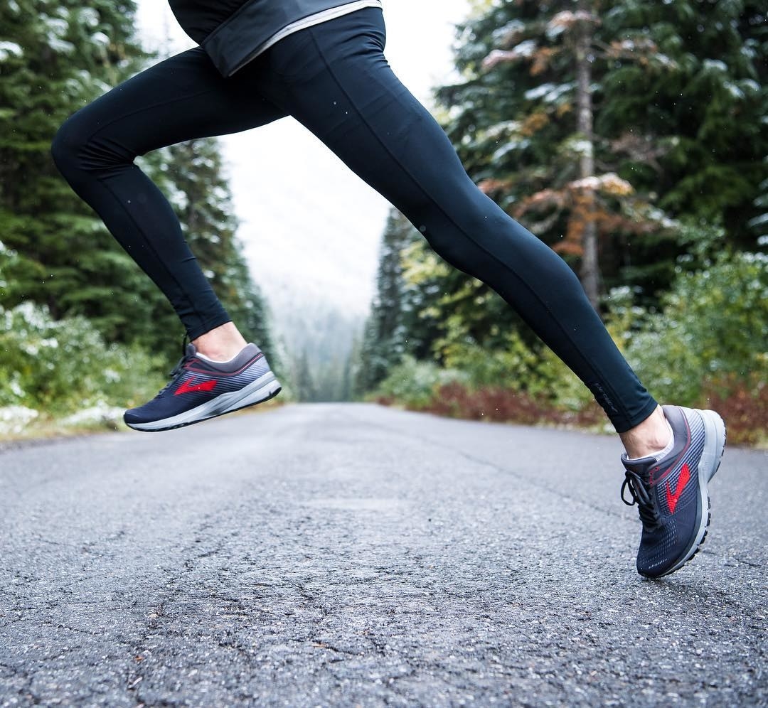 A woman running in leggings and sneakers on pavement.