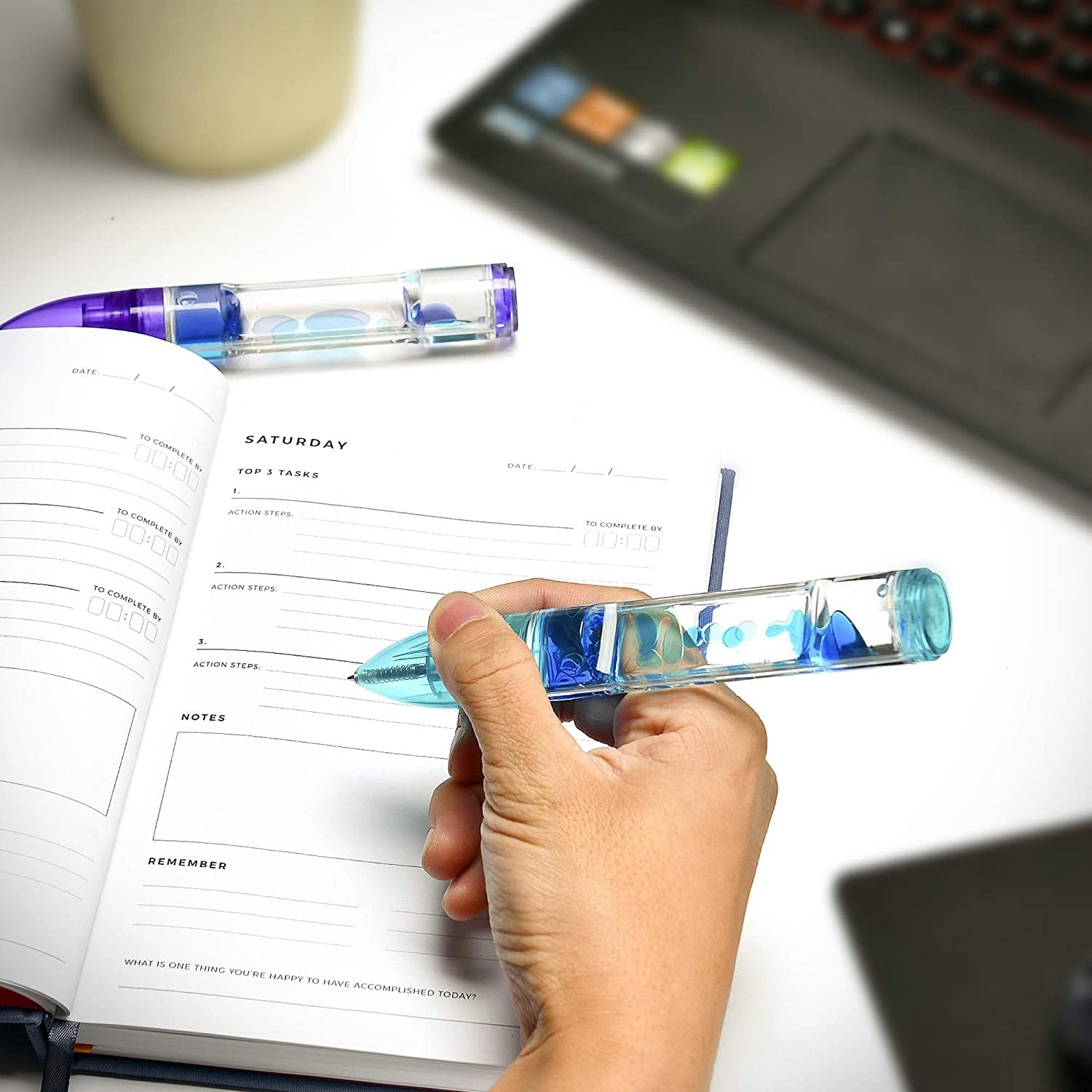 A person filling out an agenda with one of the lava lamp pens