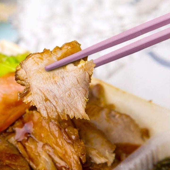 A close up of the chopsticks in action picking up some pork  