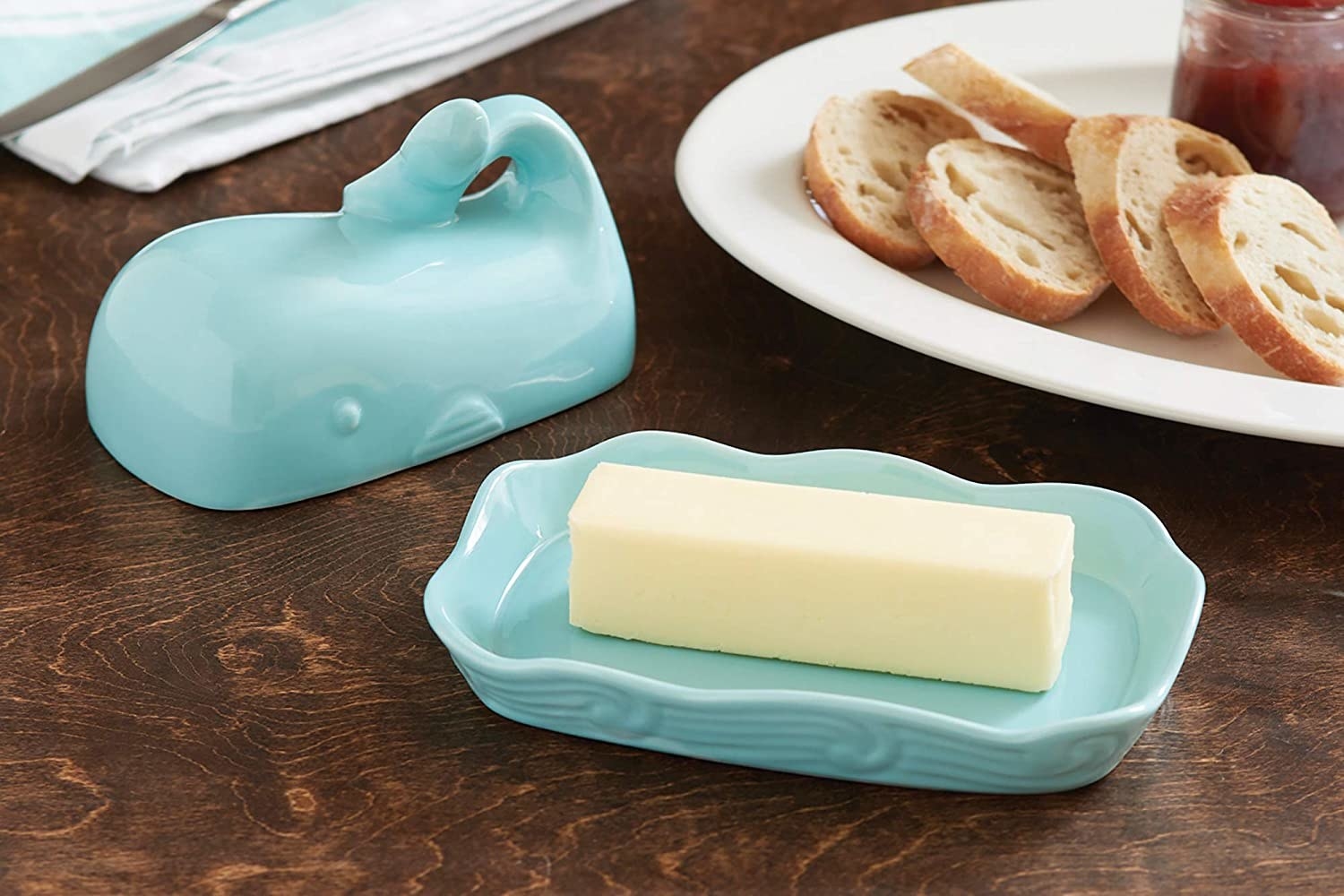 The whale-shaped butter container open on a table next to some crusty bread