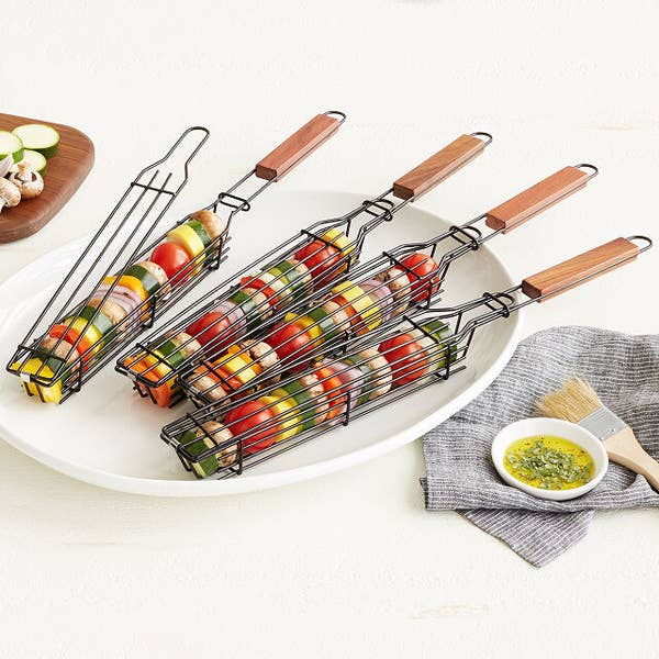 Four grilling baskets with assorted veggies in each one on a plate