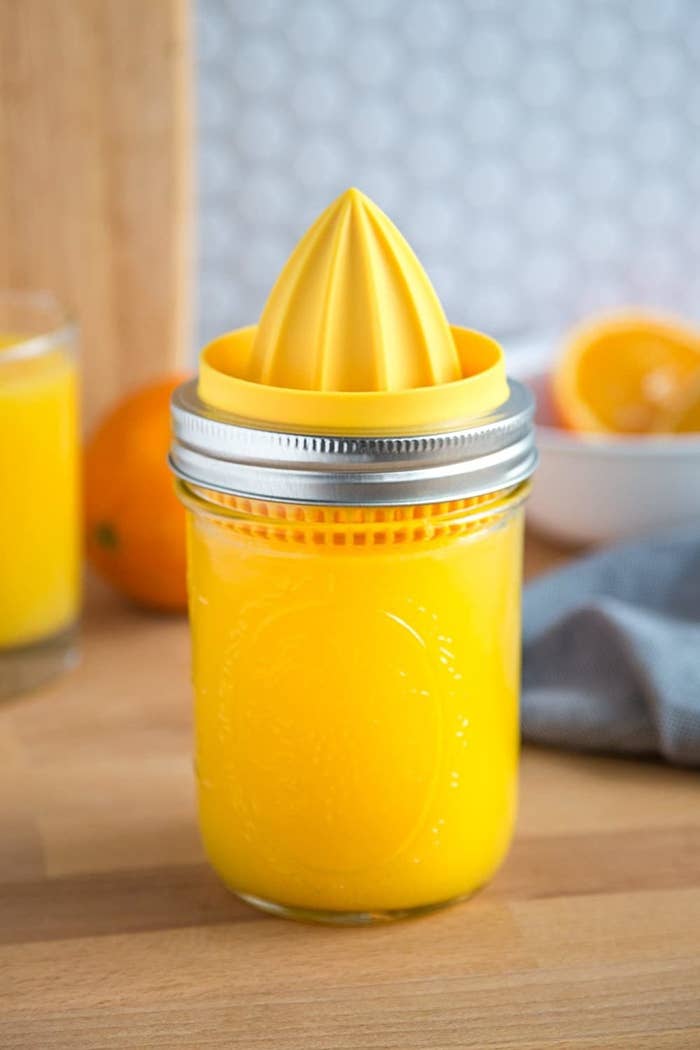 A close up of the juicer lid on a Mason jar filled with orange juice
