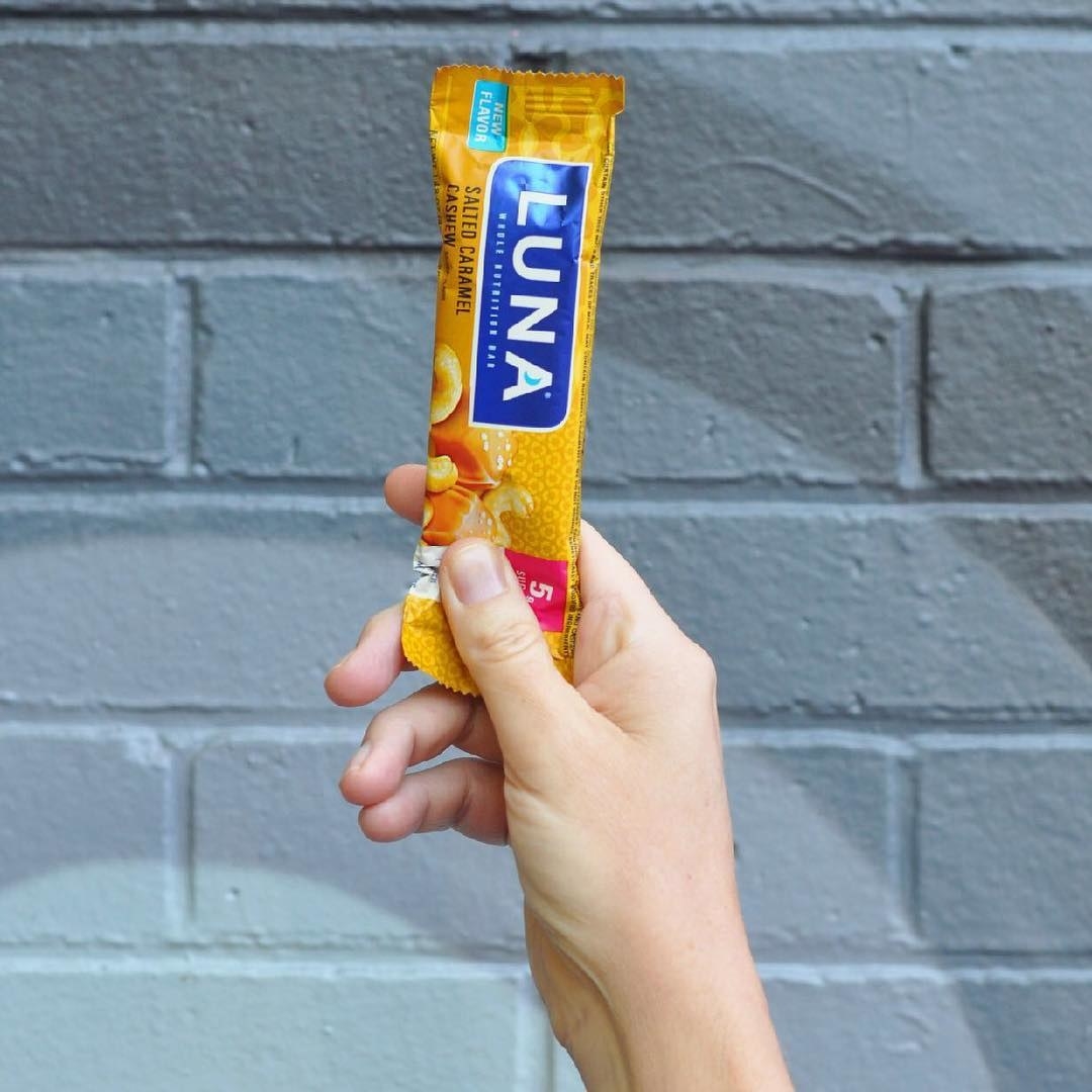Someone holding a salted caramel luna bar in hand.