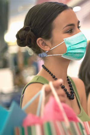 Model wearing the mask strap extender in grey on the back of their neck with a disposable mask attached to it