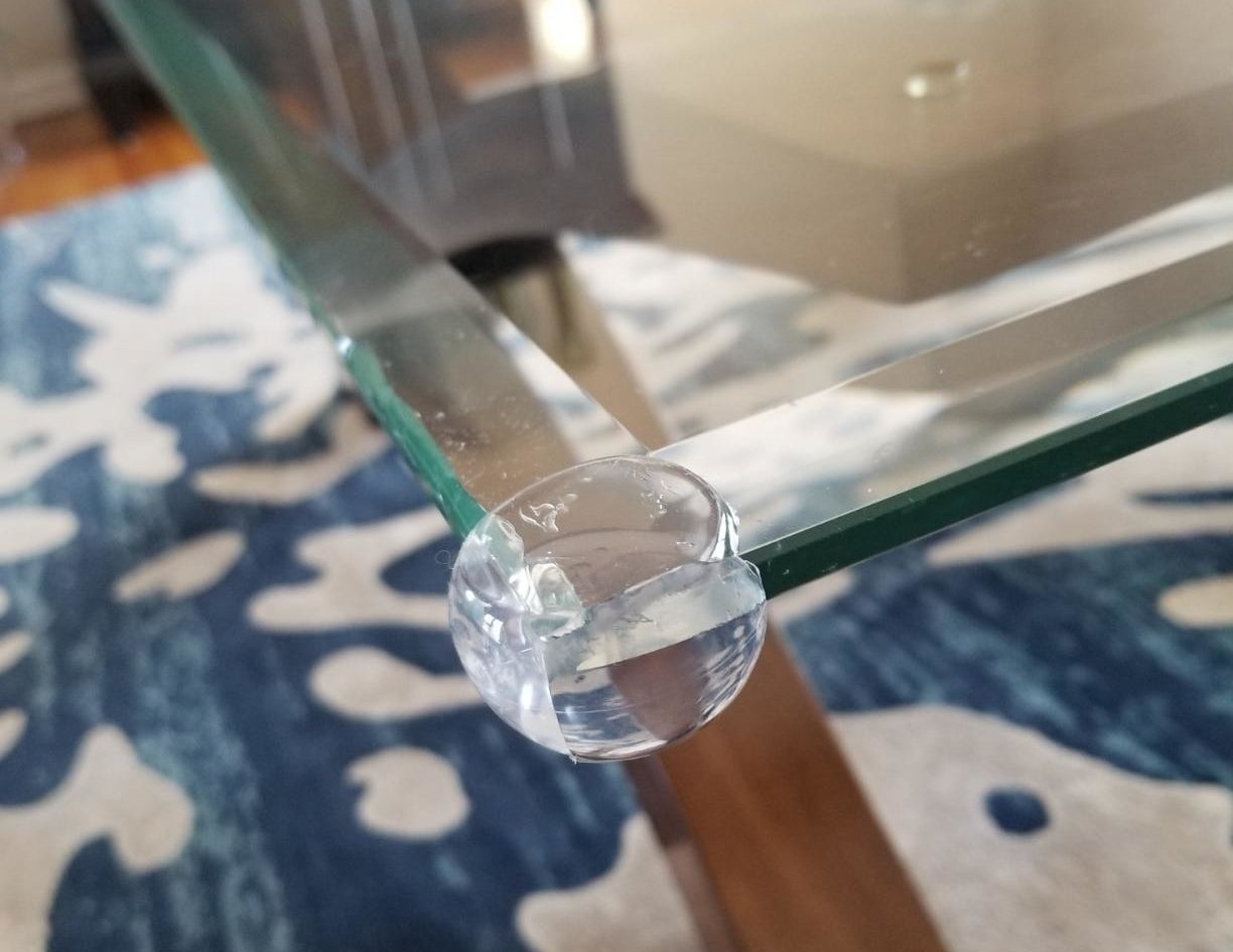 Reviewer pic of the clear protectors on the corner of a glass coffee table