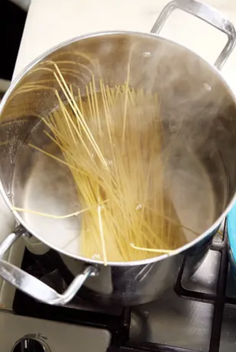 Raw spaghetti noodles dropped into a not-yet-boiling pot of water