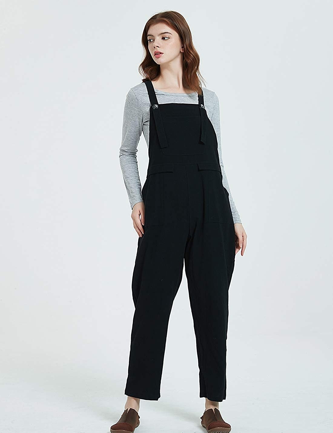 A person wearing the button-up overalls with a shirt underneath. The overalls have front pockets and hit the ankle.