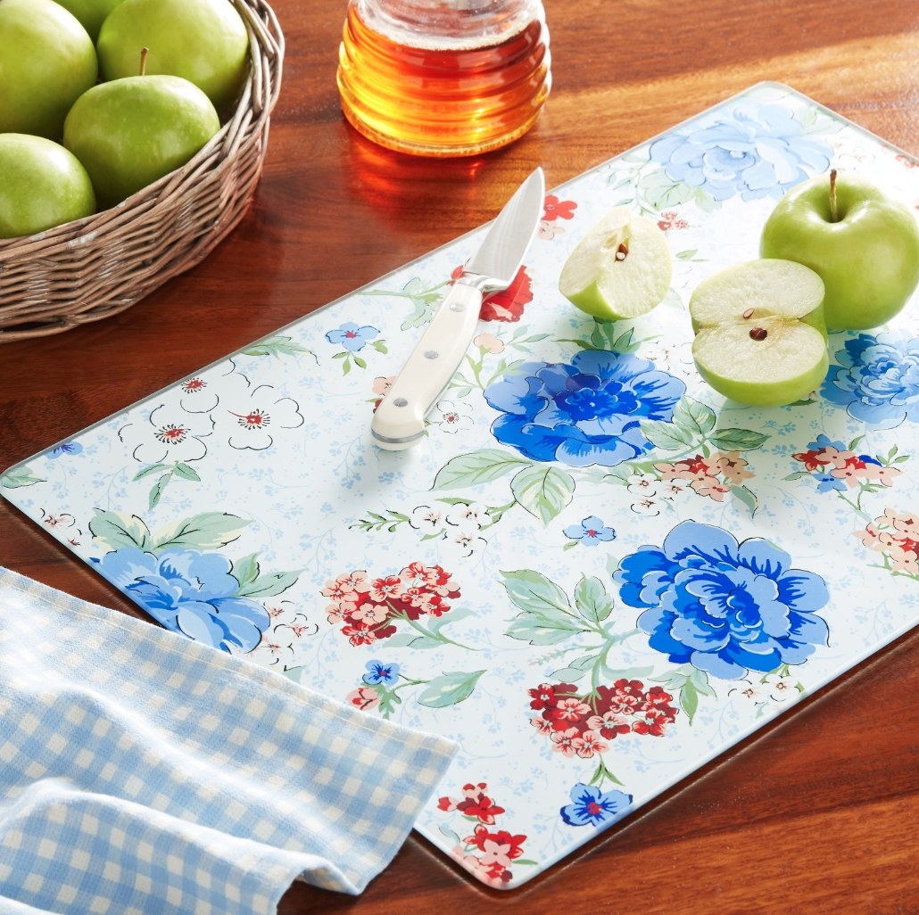 Floral-print glass cutting board sitting on dark-grain wood table