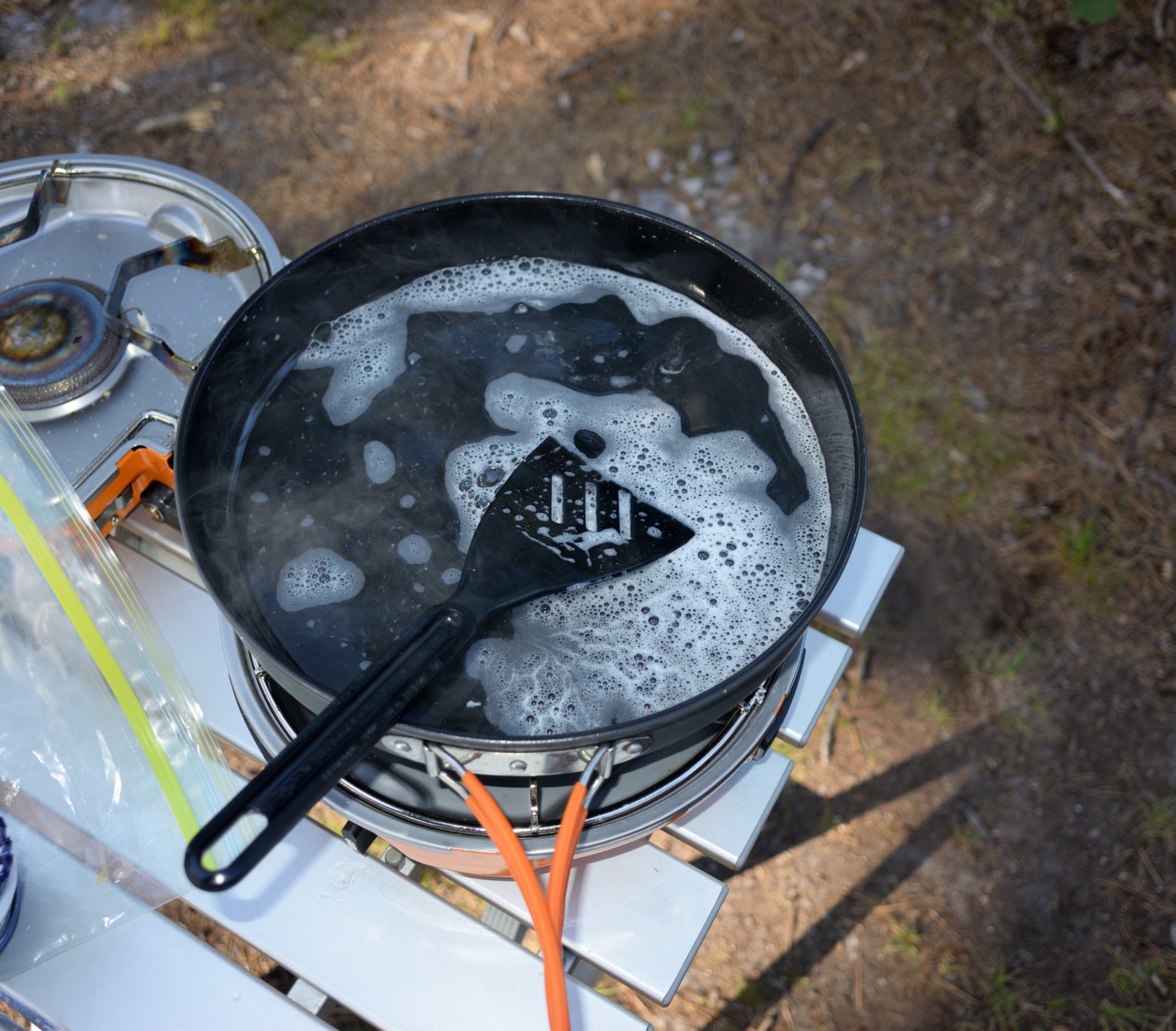 Cleaning a cooking pan and spatula on the camp stove