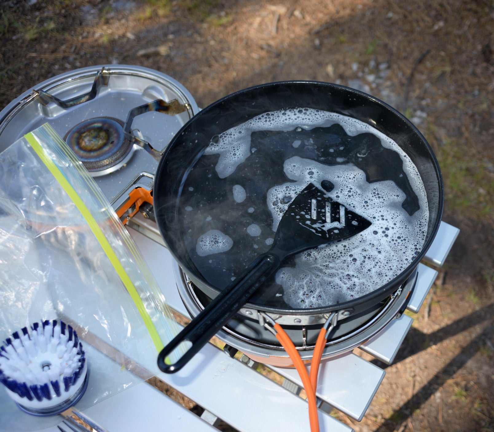 Cleaning a cooking pan and spatula on the camp stove