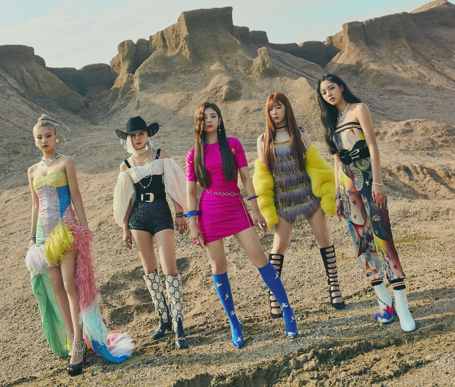 Each member of ITZY poses in the desert in high heels, dresses, and sparkling jewelry  