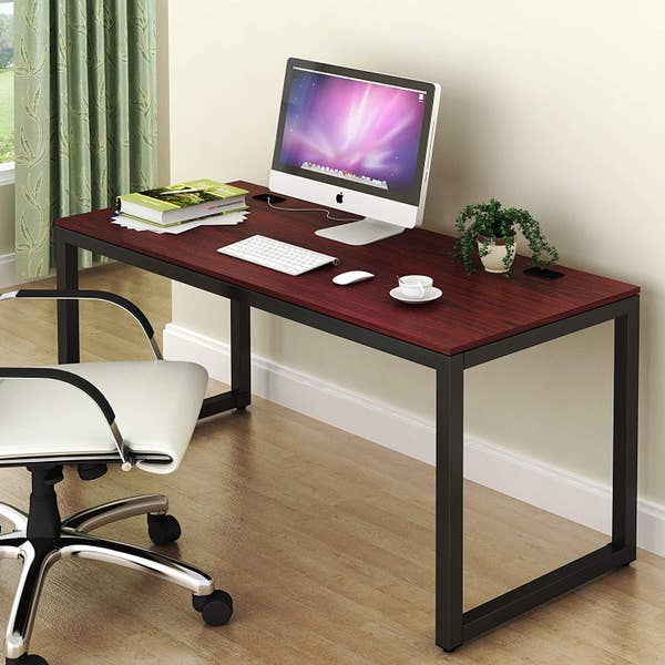 Cherry wood-like top desk with black legs with a computer on top of it