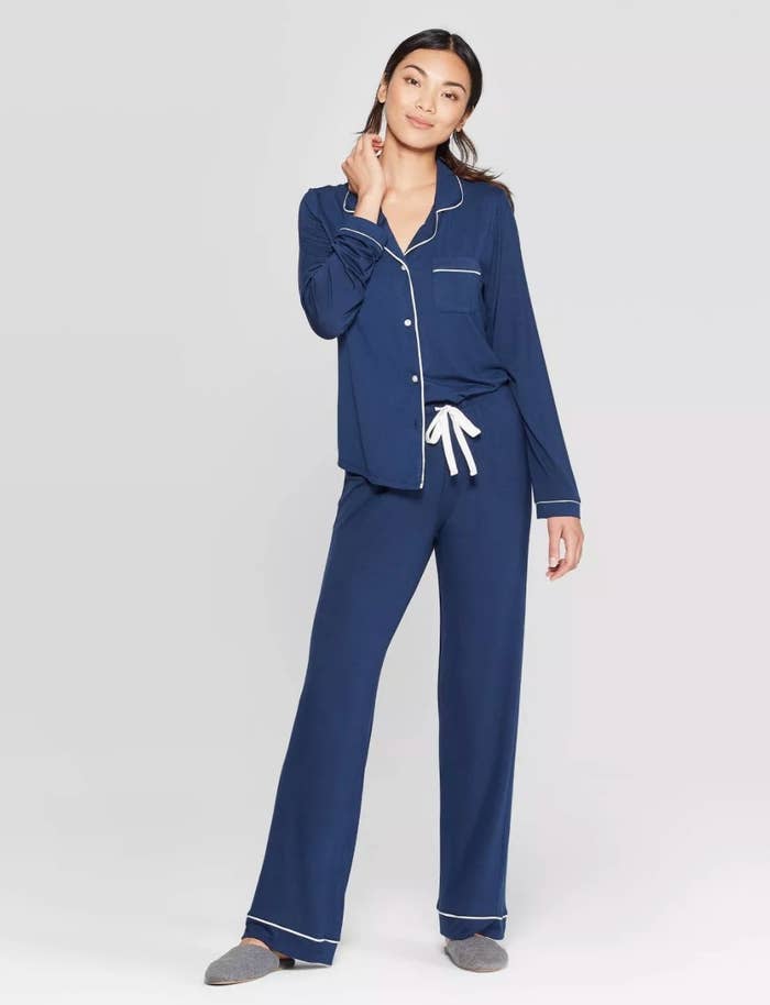 Woman wearing long-sleeve navy blue pajamas with white piping