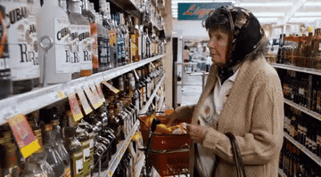 An elderly woman scanning the aisles of a liquor store.