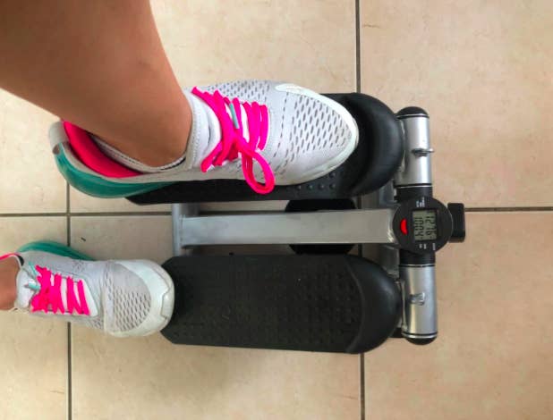 Reviewer steps on mini black stepping machine with white, gray, and pink sneakers
