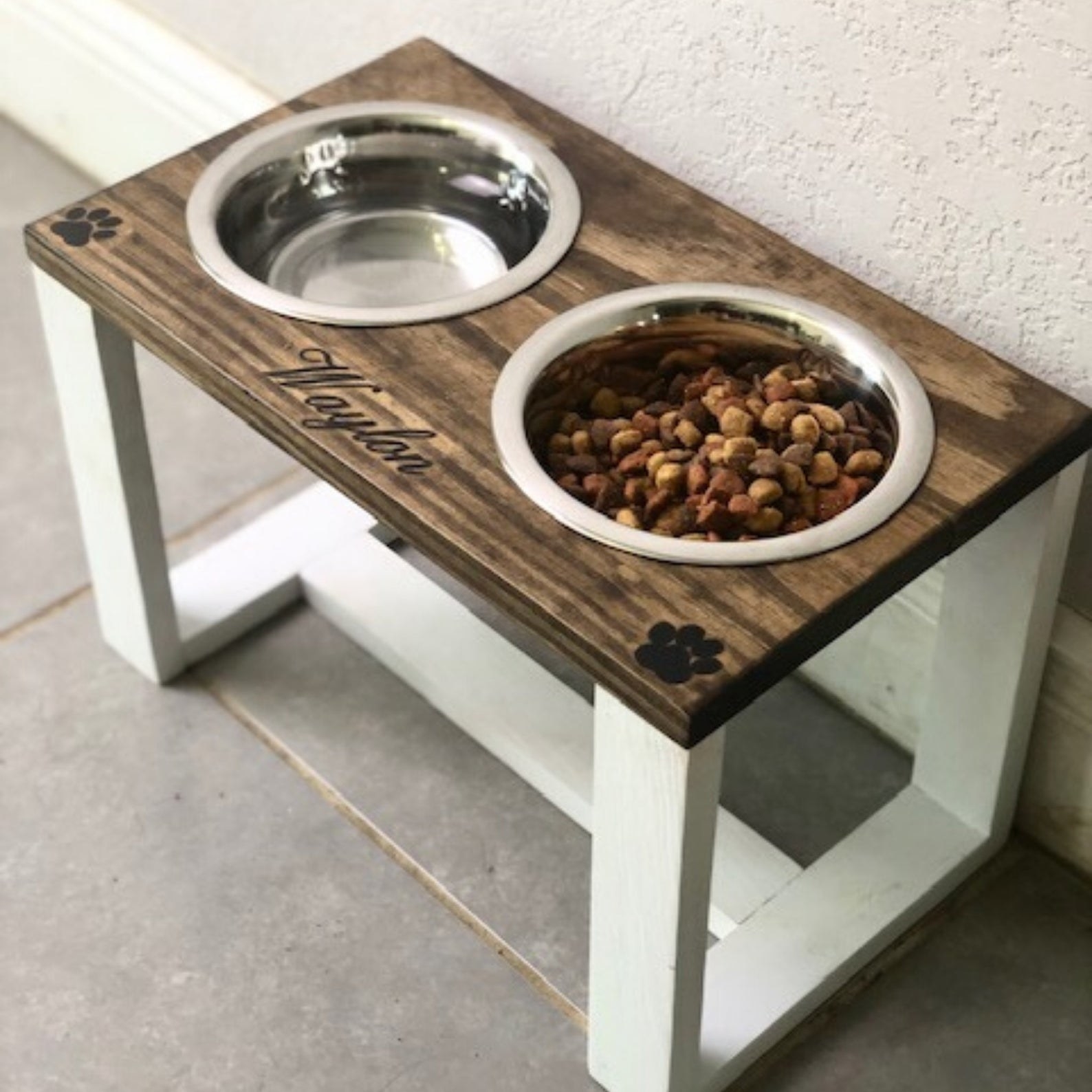 Two dog bowls lodged inside a wooden feeding station with legs for easy access