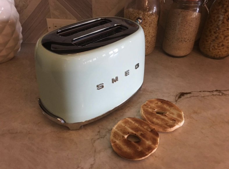 a reviewer photo of the mint colored toaster with two halves of a toasted bagel