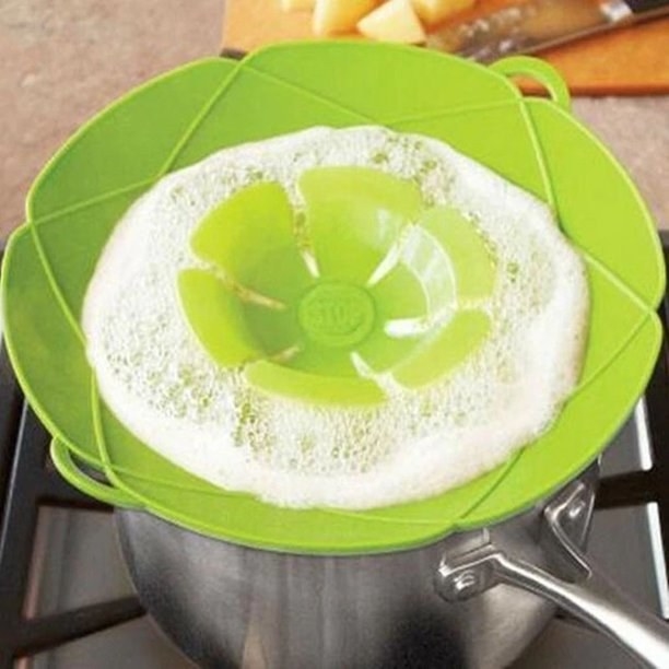 Product photo showing the SpillStopper in green preventing boiling water from spilling over the edge of a pot onto the stovetop