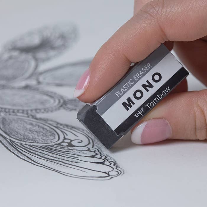A hand holds an eraser beside a drawing