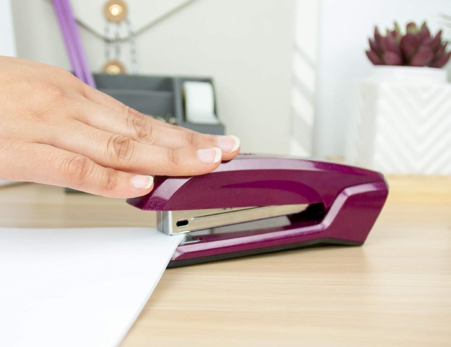 A hand pushes a stapler over a paper