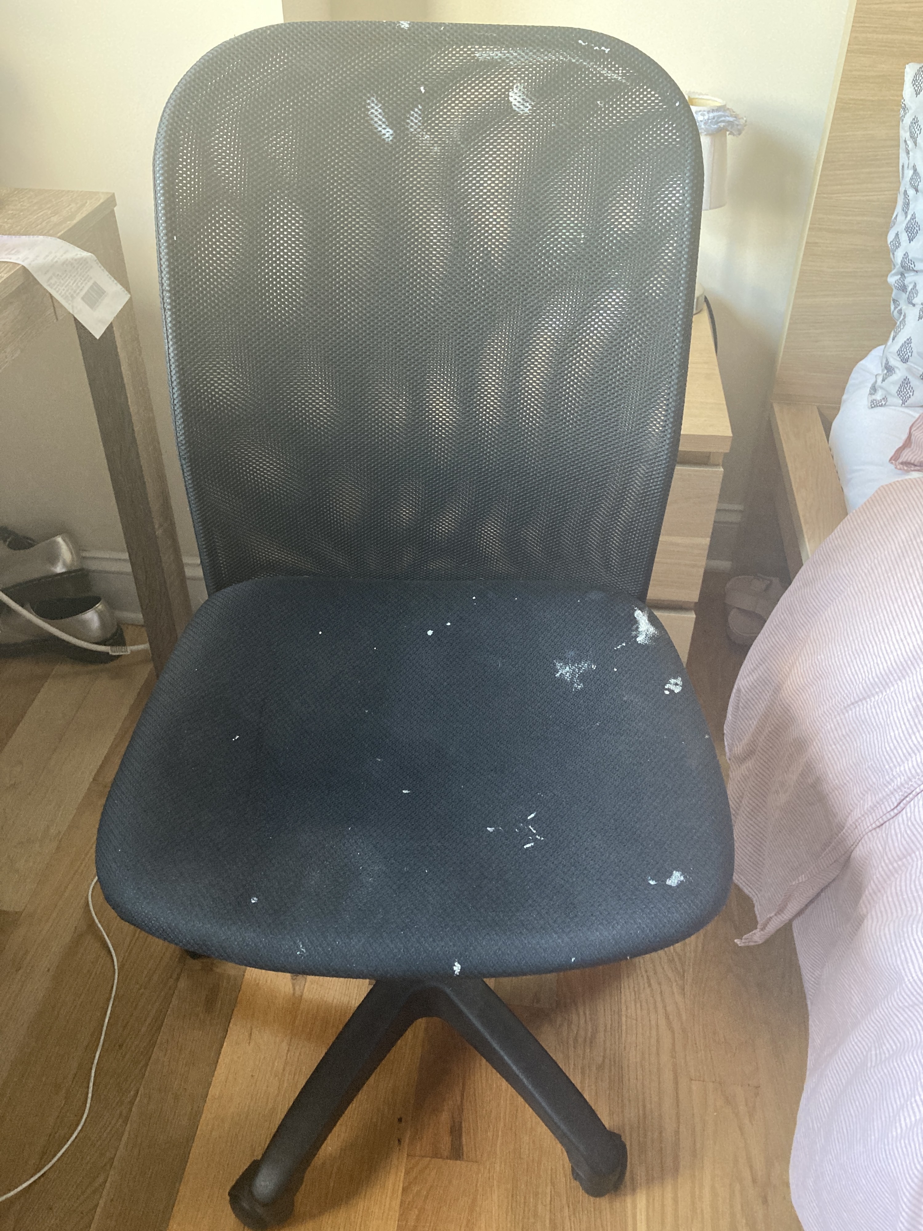 A basic desk chair covered in paint splatters