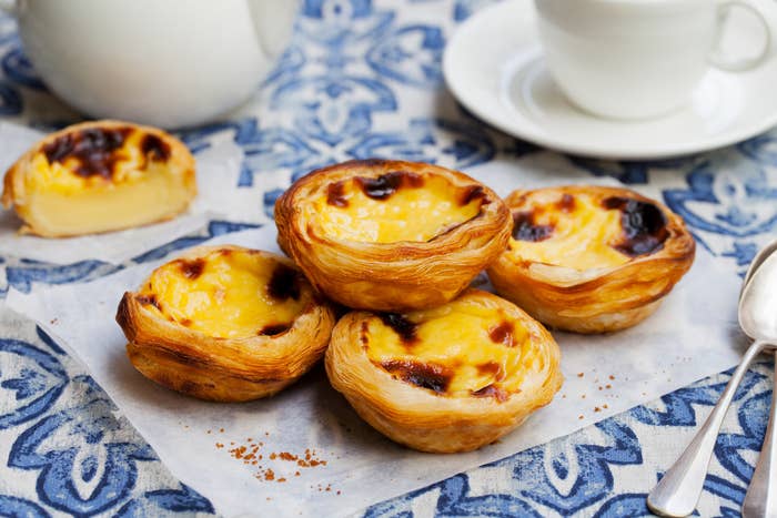 palm-sized egg custard tarts with flaky pastry on a patterned table