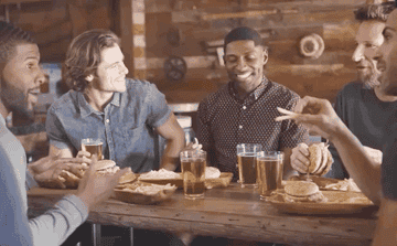 A group of male friends talk in a pub