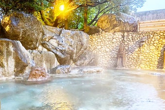 温泉の一部で、自然の岩と石垣で囲まれた静かな湯船がある風景。