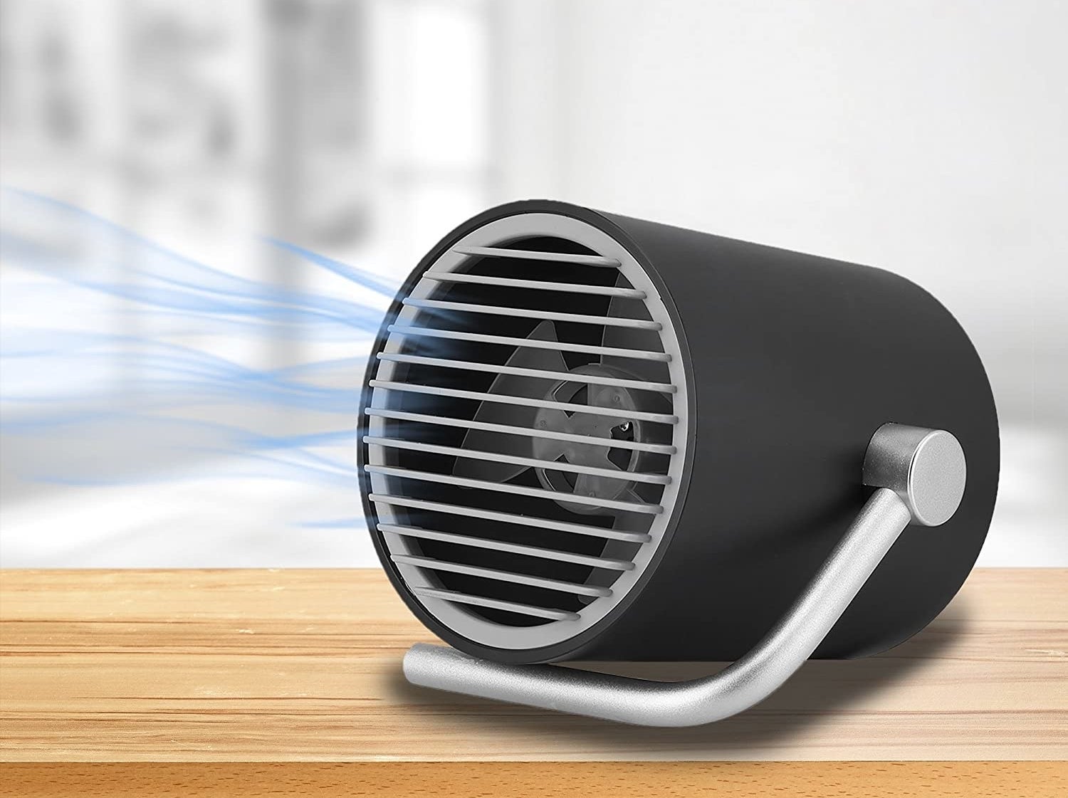 A desk fan on top of a desk blowing cold air