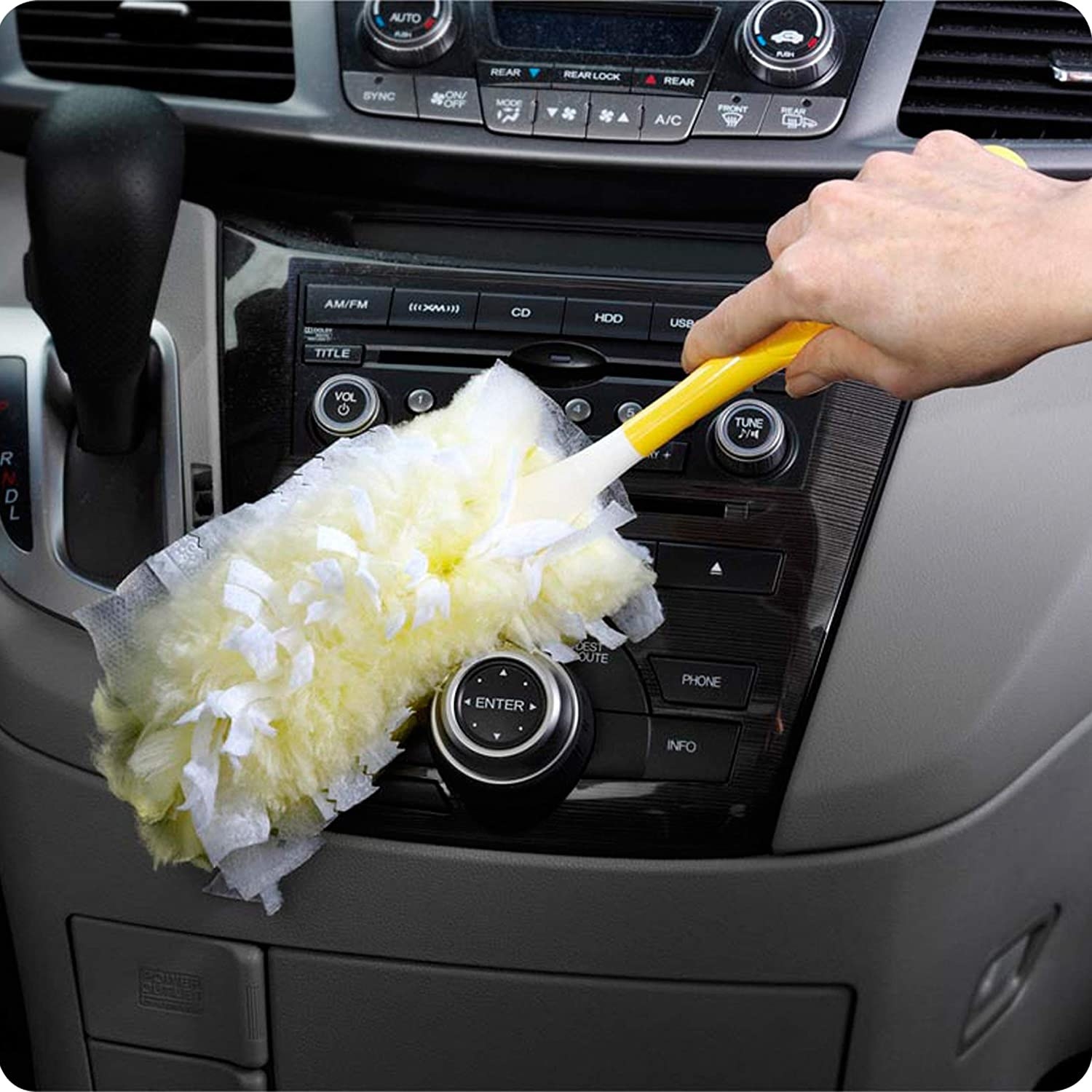 A person dusting their car with a feather duster