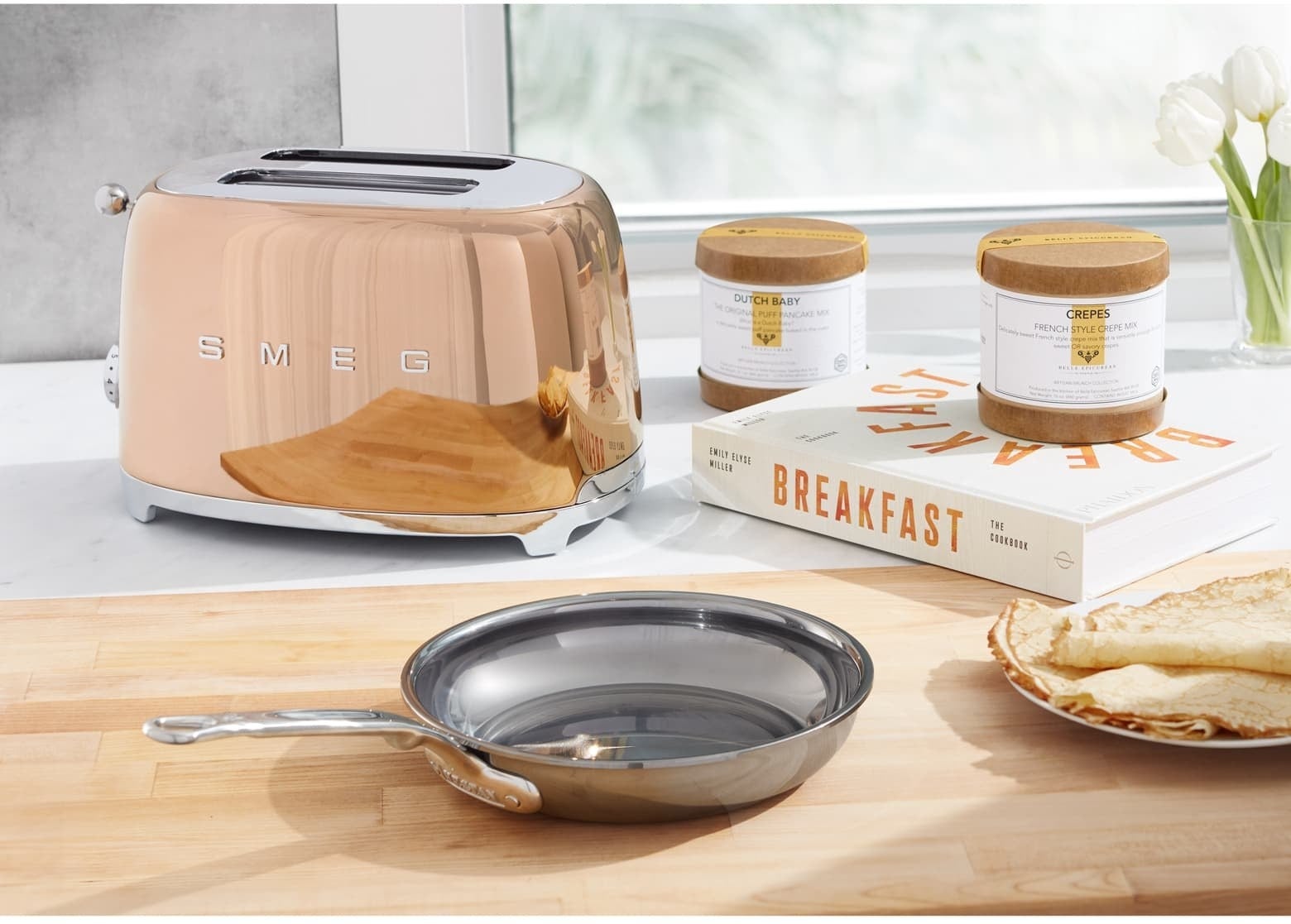 The toaster in shiny rose gold with two slots and the word &quot;Smeg&quot; on the side sitting on a kitchen counter