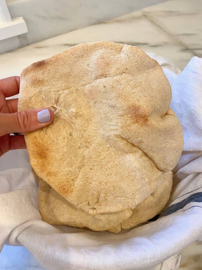 My hand holding a piece of freshly baked pita bread.