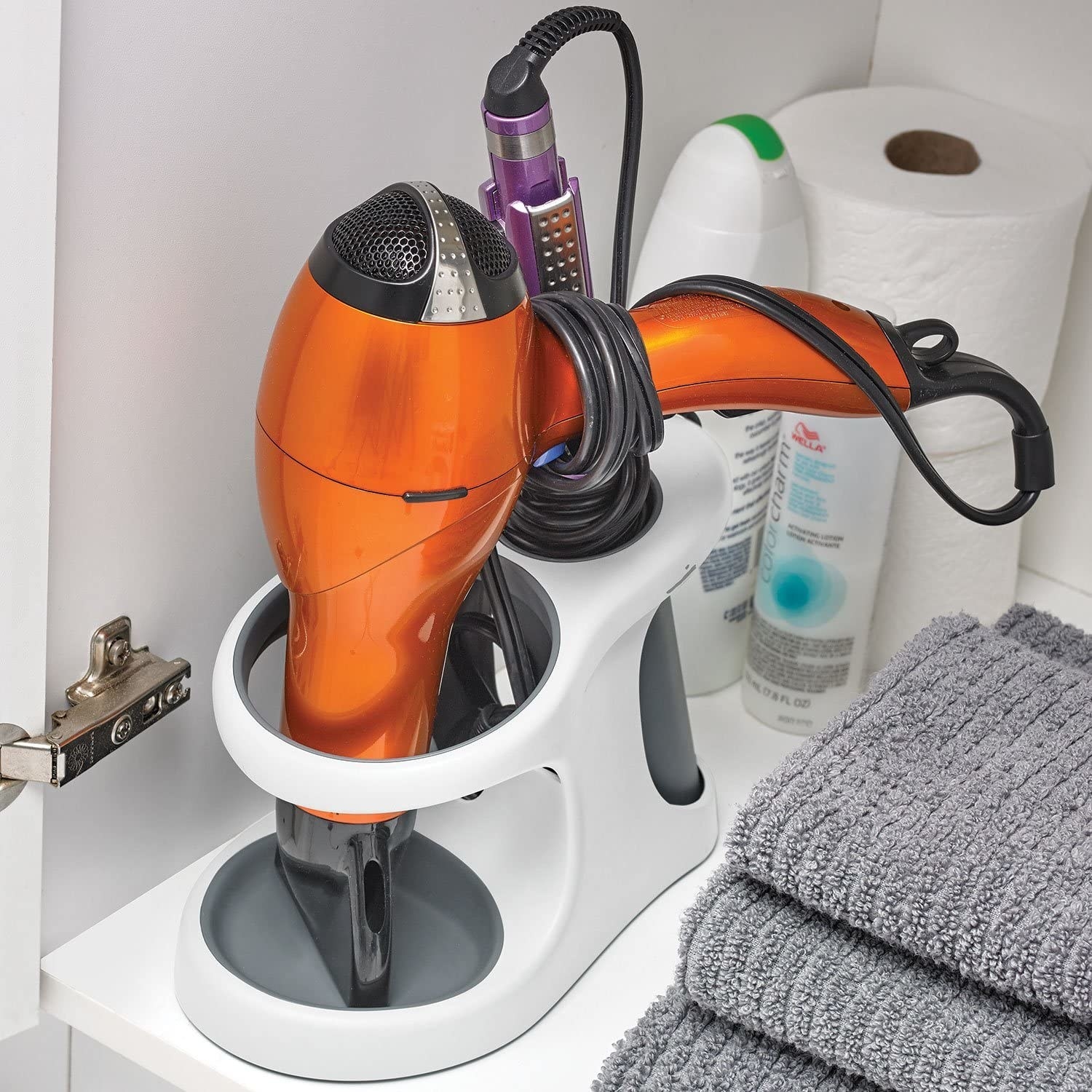 A close up of the holster in a bathroom cupboard holding a hair dryer and a straightener