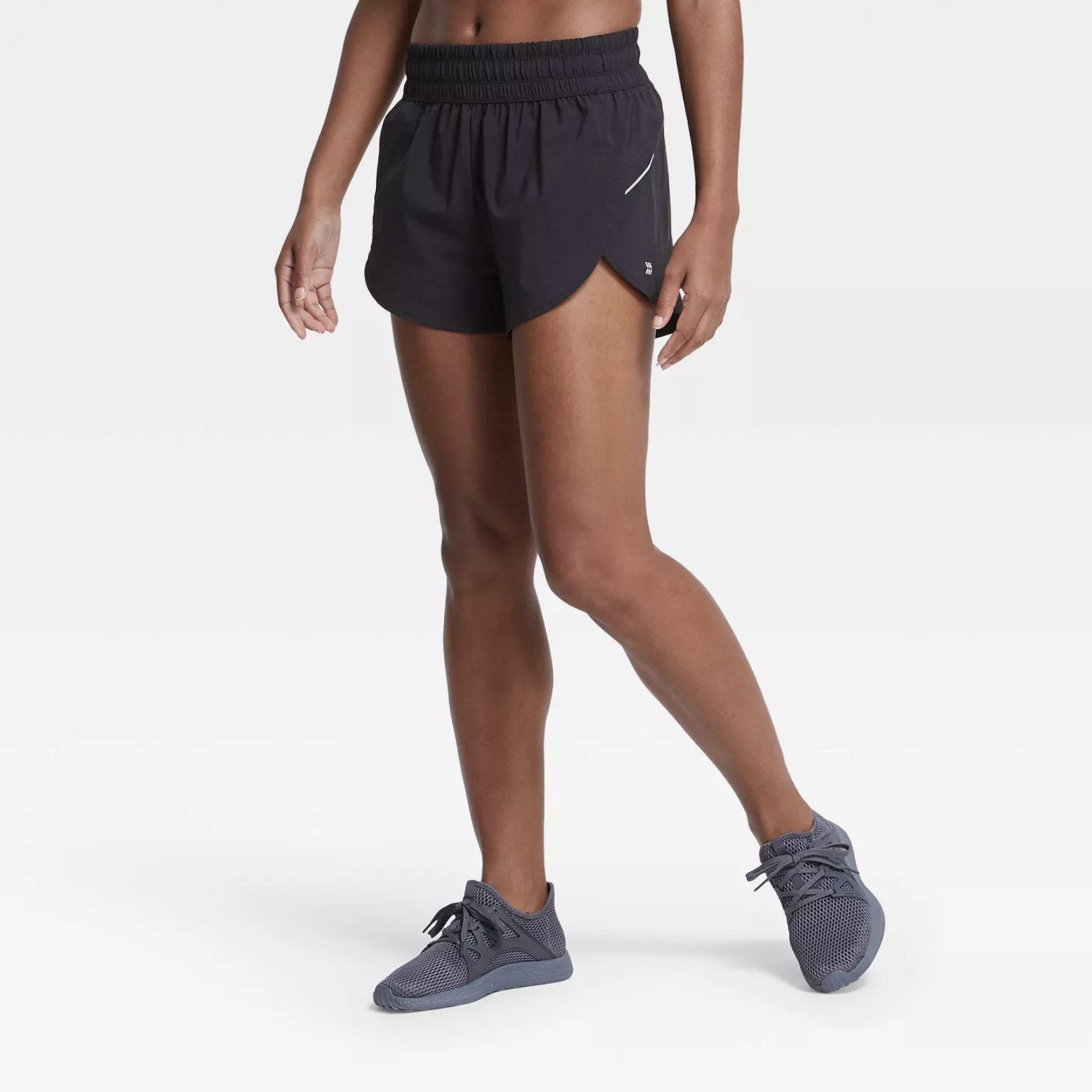 Model is wearing black run shorts with dark grey sneakers