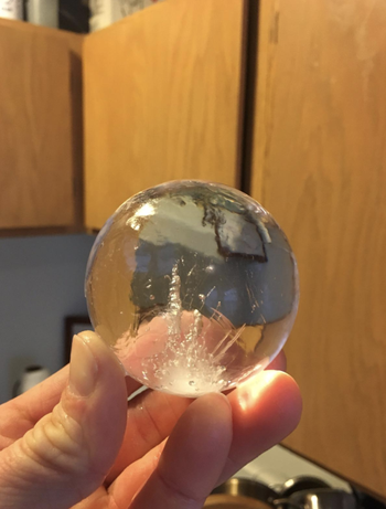 someone holding up a sphere shaped ice cube 