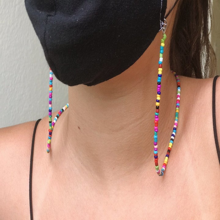 Model wearing a face mask with rainbow beaded chain attached to it 