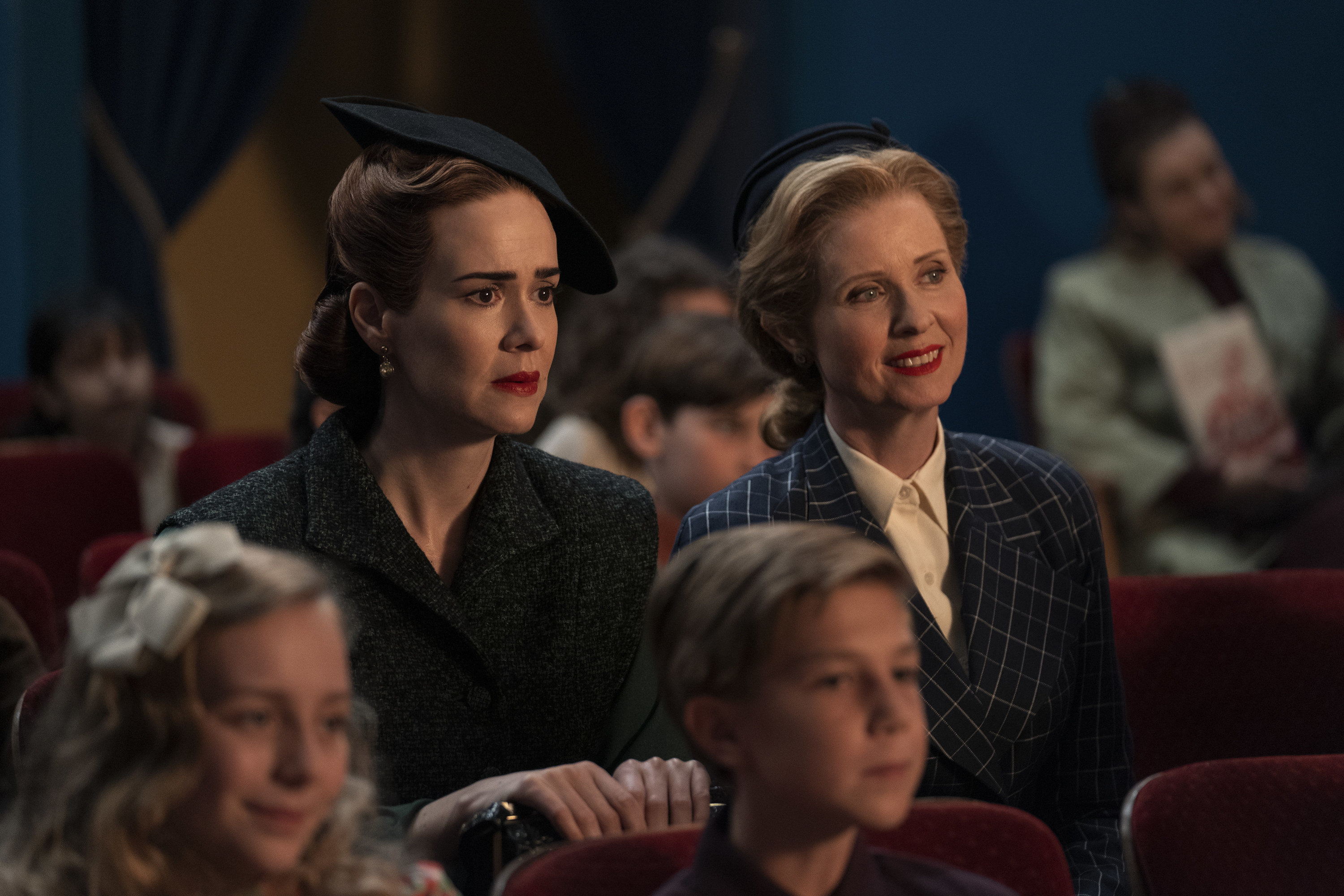 Sarah Paulson and Cynthia Nixon are seated in a theater as they look on