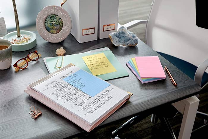 Six pads of eco-friendly Post-it notes next to documents with the sticky notes on them