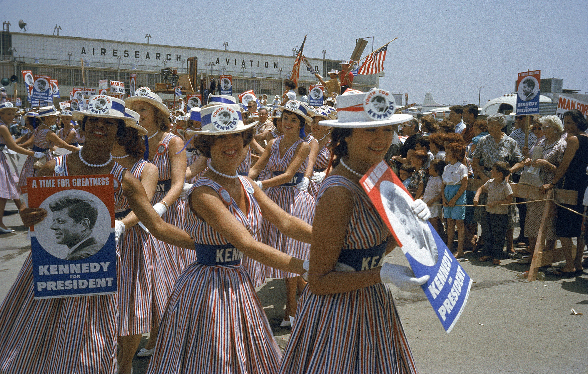 Women wearing ribbons that say Kennedy and buttons that have the face of JFK