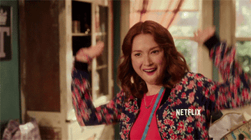 Kimmy from &quot;Unbreakable Kimmy Schmidt&quot; excitedly raises her hands as if she&#x27;s &quot;raising the roof&quot;
