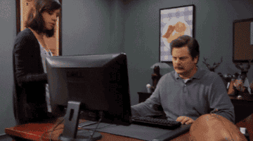 Ron Swanson from Parks and Recreation looks unhappily at his computer before tossing it in the trash