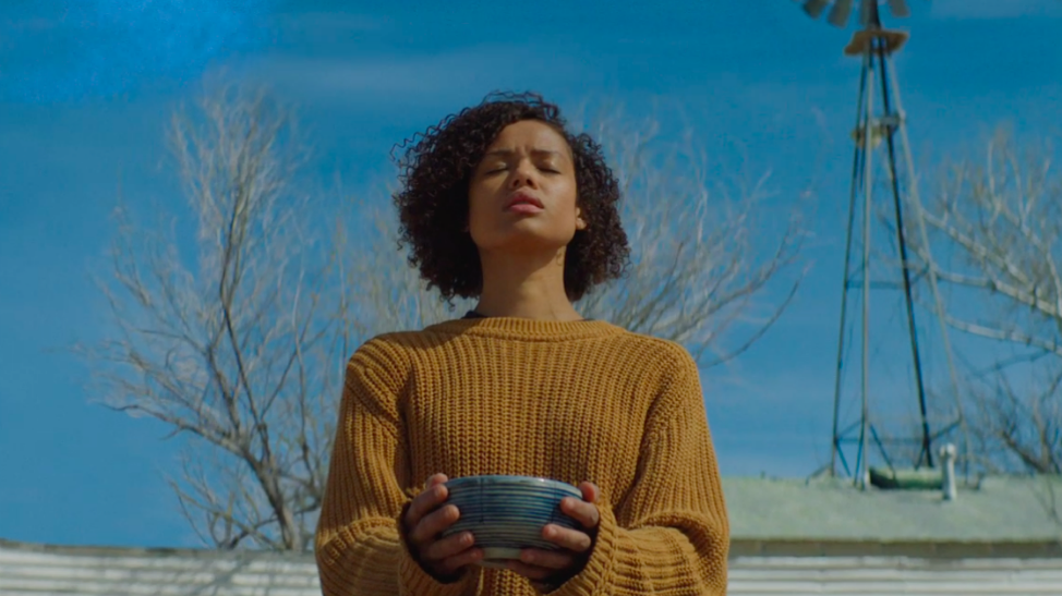 Gugu Mbatha-Raw stands outside and holds onto a ceramic bowl with her eyes closed