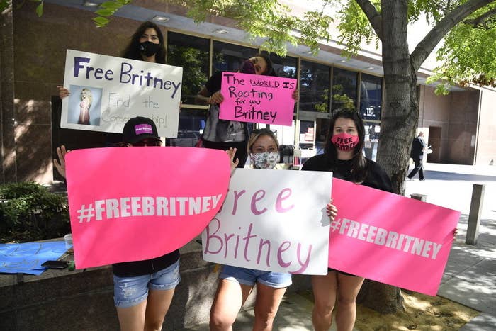 Five protesters holding signs that say "#FreeBritney" and "The world is rooting for you Britney"