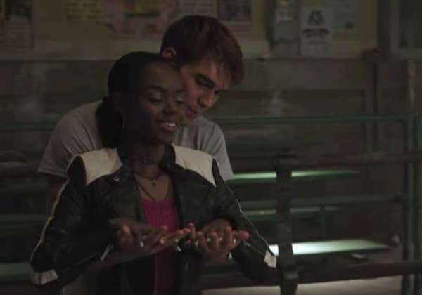 Archie holding Josie from behind as they link hands